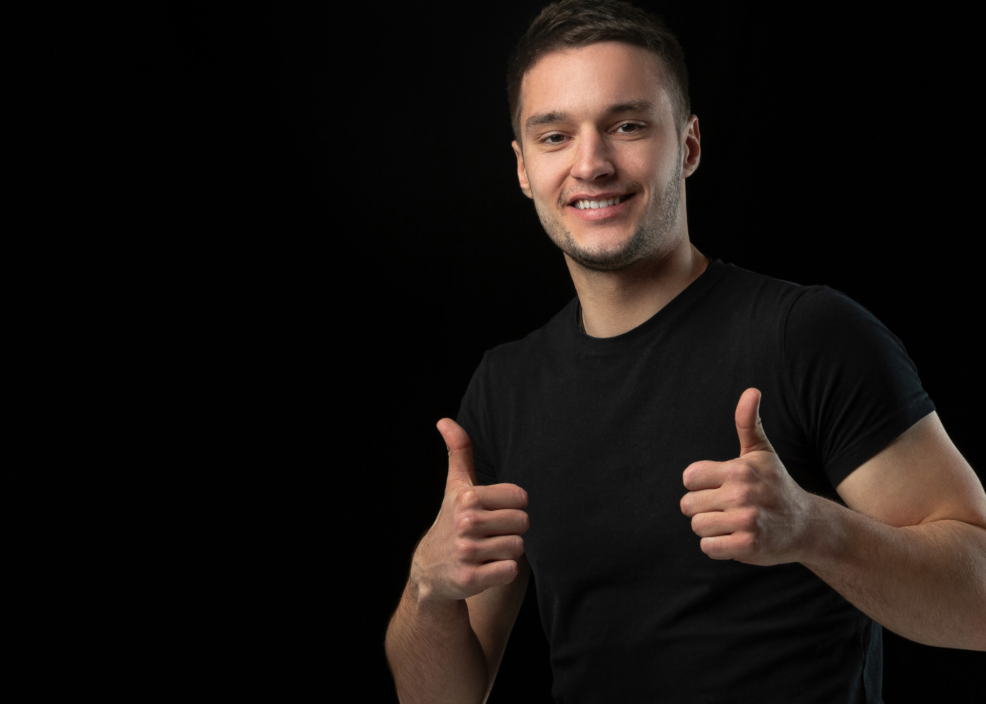 smiling-thumbs-up-monochrome-portrait-young-caucasian-man-isolated-black-studio-wall 1.jpg